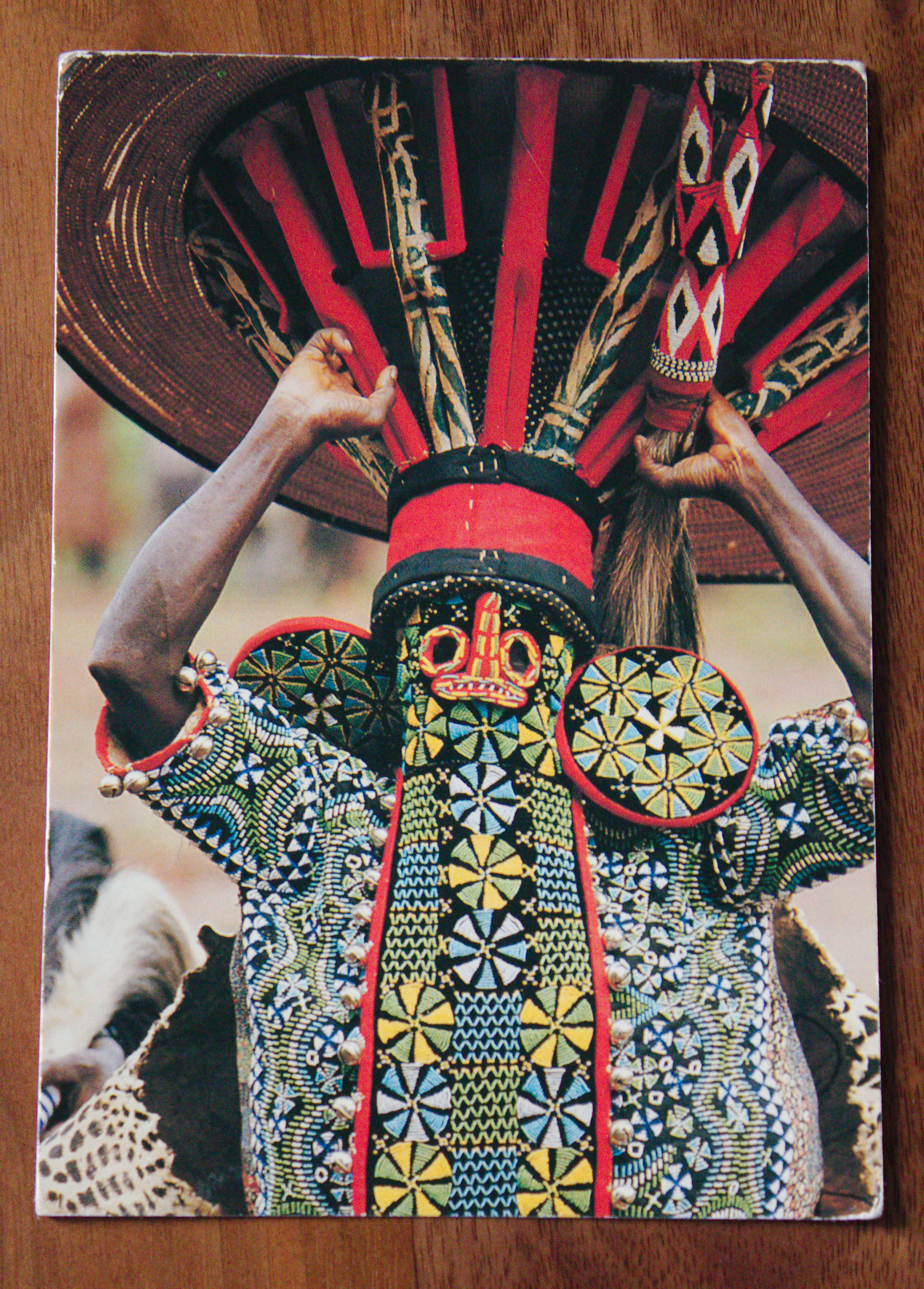 "The front of a postcard, showing a person in vibrant dress. Presumably African."